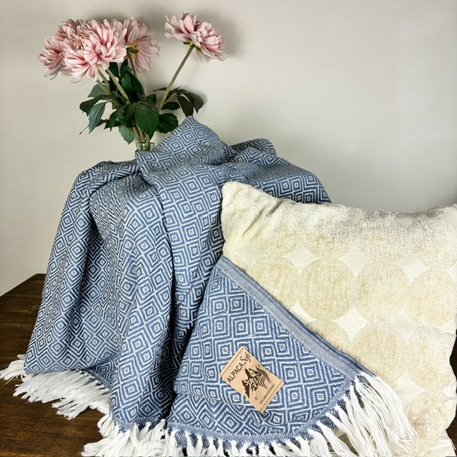 Blauw handgemaakt Alpaca deken hangt over beige kussen-1-Merani